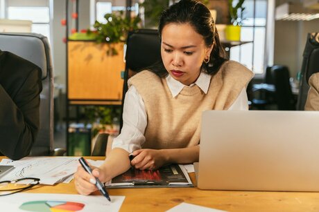 Специалист фиксирует заметки по задаче рядом с ноутбуком
