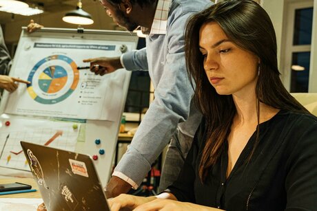 Команда обсуждает фронтенд-задачи у ноутбука и проектной доски